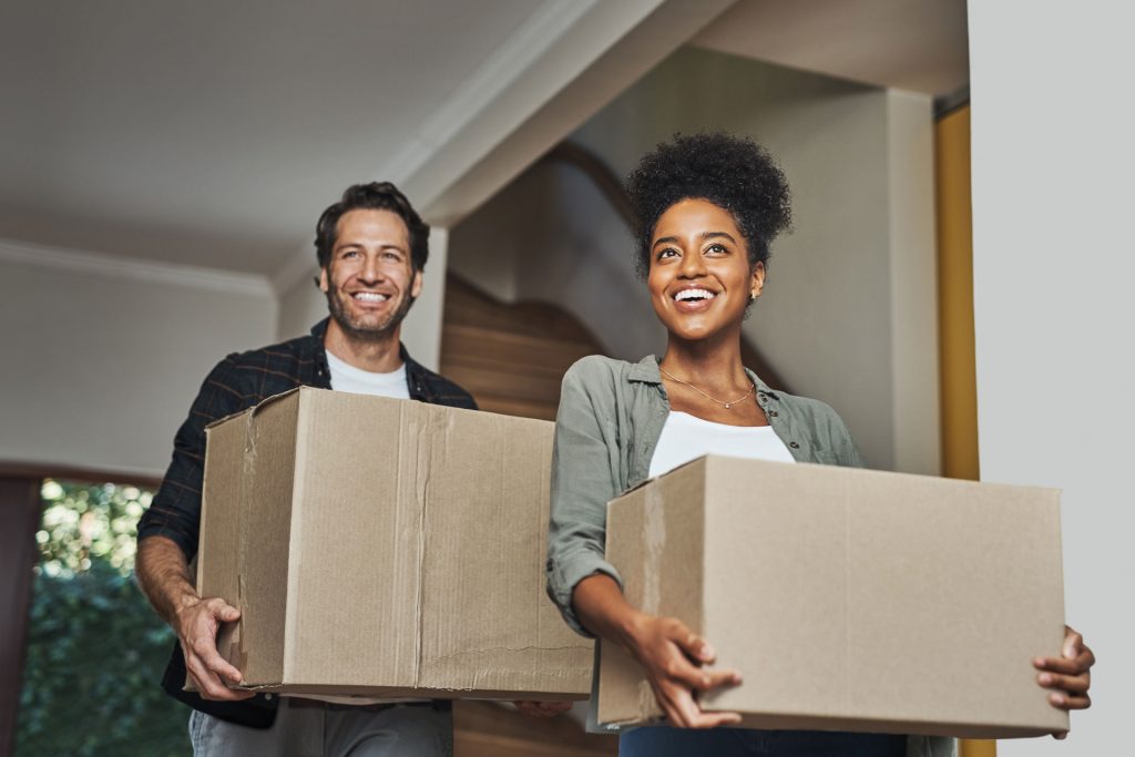 An image of a happy young couple holding packing boxes.