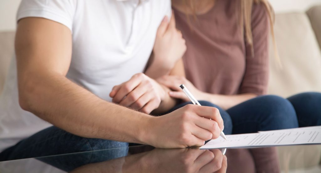 A close-up image of a man signing a document.