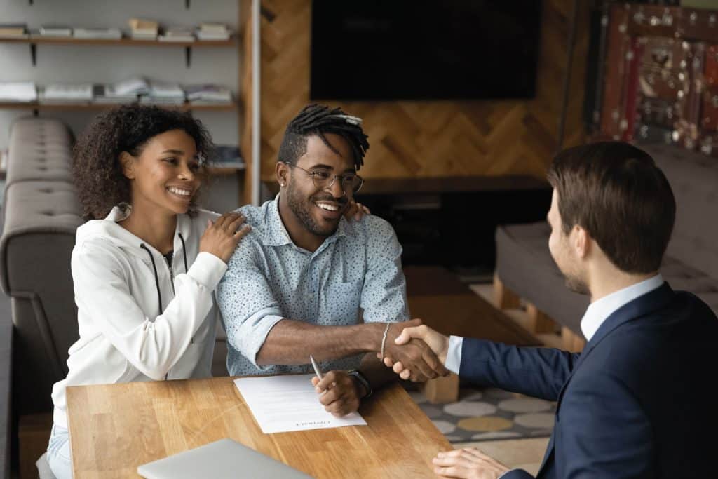 An image of a couple shaking hands with a professional looking man.